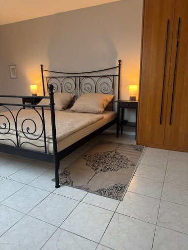 Schlafzimmer mit einem Eisenbett, Nachttischen und einem Holzschrank. Helles, gemütliches Ambiente.