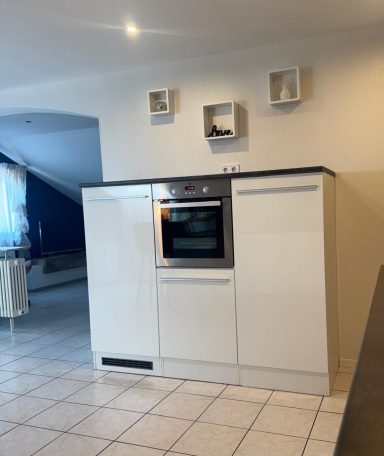 Moderne, weiße Küche mit einem eingebauten Ofen und offenen Regalen an der Wand.