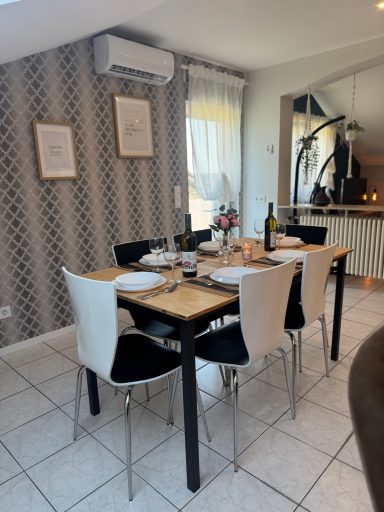 Esstisch mit vier Stühlen, gedeckt mit Geschirr und Weinflaschen in modernem Raum.