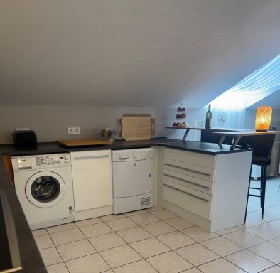 Küche im Dachgeschoss mit Waschmaschine, Geschirrspüler und Blick auf Fenster.