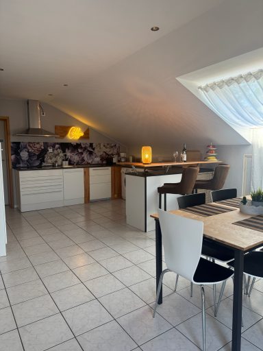 Helle, moderne Küche mit Essbereich und großen Fenstern unter dem Dach.