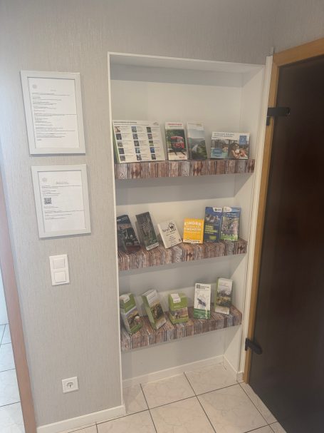 Regal mit Informationsmaterial und Broschüren an einer Wand.